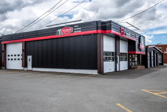 Le bâtiment de Jolibois Pneus et Mécanique vu de la rue, avec ses portes de garage et son liseré rouge